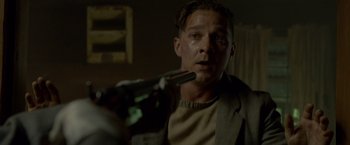 Movie still from “Lawless” (2012), directed by John Hillcoat – A man holding a gun in a room with lights on; Close Up shot, Low angle