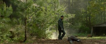 Movie still from “Lawless” (2012), directed by John Hillcoat – A man walking in the woods next to a dead body; Wide shot, Low angle