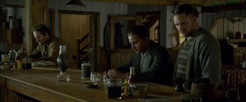 Movie still from “Lawless” (2012), directed by John Hillcoat – A man sitting at a wooden table in front of a bowl of food; Medium shot, High angle