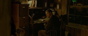 Movie still from “Lawless” (2012), directed by John Hillcoat – A man sitting in front of a computer in a dark room; Medium shot, High angle