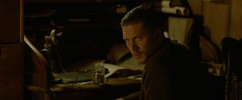 Movie still from “Lawless” (2012), directed by John Hillcoat – A person sitting at a table; Close Up shot, Over the shoulder angle