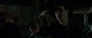 Movie still from “Lawless” (2012), directed by John Hillcoat – A man holding a gun while wearing a black hat; Close Up shot, Over the shoulder angle