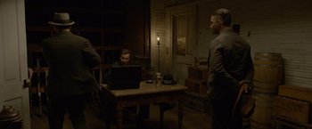 Movie still from “Lawless” (2012), directed by John Hillcoat – A man sitting in front of a laptop computer; Wide shot, Over the shoulder angle