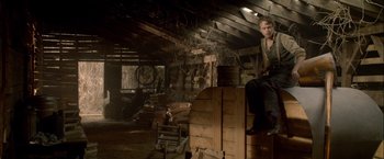 Movie still from “Lawless” (2012), directed by John Hillcoat – A man sitting on top of a wooden structure; Wide shot, Low angle
