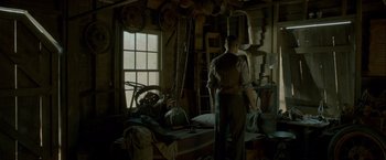 Movie still from “Lawless” (2012), directed by John Hillcoat – A man standing in front of a window in a room; Wide shot, Low angle
