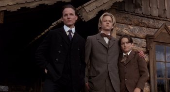 Movie still from “Legends of the Fall” (1994), directed by Edward Zwick – Three men in suits and ties standing next to each other in front of a building; Medium shot, Low angle
