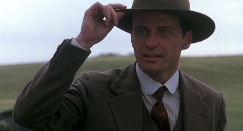 Movie still from “Legends of the Fall” (1994), directed by Edward Zwick – A man in a suit and tie holding his hat up; Close Up shot, Low angle