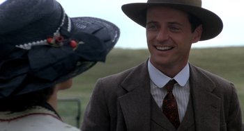 Movie still from “Legends of the Fall” (1994), directed by Edward Zwick – A man wearing a suit and a hat and smiling; Close Up shot, Over the shoulder angle