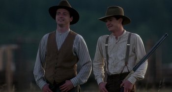 Movie still from “Legends of the Fall” (1994), directed by Edward Zwick – A couple of men standing next to each other wearing hats; Medium shot, Low angle