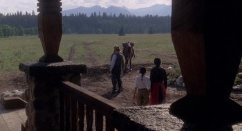 Movie still from “Legends of the Fall” (1994), directed by Edward Zwick – A group of people standing on top of a grass covered field; Wide shot, Over the shoulder angle