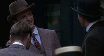 Movie still from “Legends of the Fall” (1994), directed by Edward Zwick – A man wearing a suit and hat talking to two other men; Close Up shot, Over the shoulder angle