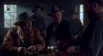 Movie still from “Legends of the Fall” (1994), directed by Edward Zwick – A group of men sitting at a table with a beer; Medium shot, Over the shoulder angle