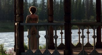 Movie still from “Legends of the Fall” (1994), directed by Edward Zwick – A woman standing on a pier near a body of water; Wide shot, Over the shoulder angle