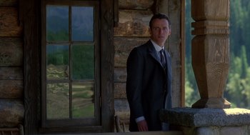 Movie still from “Legends of the Fall” (1994), directed by Edward Zwick – A man standing in front of a wooden building; Medium shot, Low angle