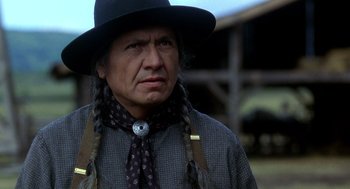 Movie still from “Legends of the Fall” (1994), directed by Edward Zwick – A man in a black hat and a black tie; Close Up shot, Over the shoulder angle