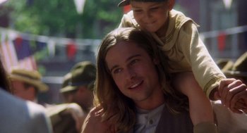 Movie still from “Legends of the Fall” (1994), directed by Edward Zwick – A man with long brown hair is holding a boy on his shoulders; Close Up shot, Over the shoulder angle