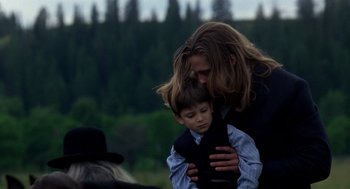 Movie still from “Legends of the Fall” (1994), directed by Edward Zwick – A man and a boy are hugging in a field; Medium shot, Over the shoulder angle