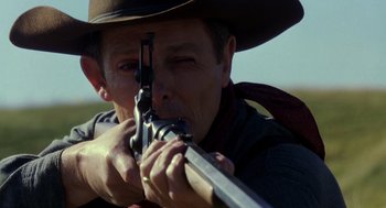 Movie still from “Legends of the Fall” (1994), directed by Edward Zwick – A man in a cowboy hat is aiming a rifle; Close Up shot, Over the shoulder angle