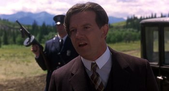 Movie still from “Legends of the Fall” (1994), directed by Edward Zwick – A man in a suit and tie standing next to a man in a uniform; Close Up shot, Low angle