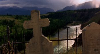 Movie still from “Legends of the Fall” (1994), directed by Edward Zwick – An old grave with a cross on top of it near a river; Wide shot, Low angle