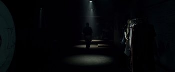 Movie still from “Lights Out” (2016), directed by David F. Sandberg – A person walking in a dark room with a light shining on them; Wide shot, Low angle