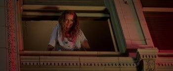Movie still from “Lights Out” (2016), directed by David F. Sandberg – A woman with pink hair looking out of a window; Medium shot, Low angle