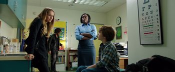 Movie still from “Lights Out” (2016), directed by David F. Sandberg – A group of people in a room with books and a clock; Medium shot, Over the shoulder angle