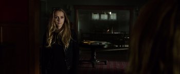 Movie still from “Lights Out” (2016), directed by David F. Sandberg – A woman standing in a dark room in front of a table; Medium shot, Over the shoulder angle