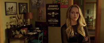 Movie still from “Lights Out” (2016), directed by David F. Sandberg – A woman sitting in front of a poster of avenged sevenfold; Medium shot, Over the shoulder angle