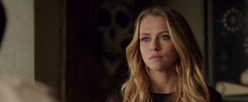 Movie still from “Lights Out” (2016), directed by David F. Sandberg – A beautiful blonde woman with a skull in the background; Close Up shot, Over the shoulder angle