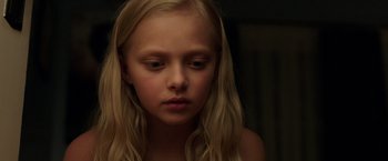 Movie still from “Lights Out” (2016), directed by David F. Sandberg – A young girl with long blonde hair looking sad; Close Up shot, High angle