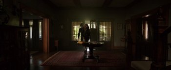Movie still from “Lights Out” (2016), directed by David F. Sandberg – A man and a woman standing in front of a table in a dark room; Wide shot, Low angle