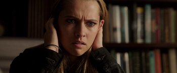Movie still from “Lights Out” (2016), directed by David F. Sandberg – A woman with her hands behind her ears; Close Up shot, Over the shoulder angle