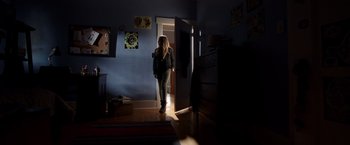 Movie still from “Lights Out” (2016), directed by David F. Sandberg – A woman standing in a dark room in front of a door; Wide shot, Low angle