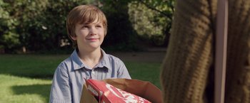 Movie still from “Lights Out” (2016), directed by David F. Sandberg – A young boy holding a bag of food in a park; Close Up shot, Over the shoulder angle