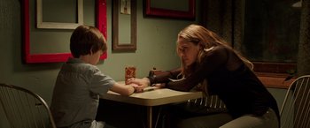 Movie still from “Lights Out” (2016), directed by David F. Sandberg – A woman and a boy sitting at a table; Medium shot, Over the shoulder angle