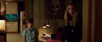 Movie still from “Lights Out” (2016), directed by David F. Sandberg – A woman standing next to a young boy in a room; Medium shot, Over the shoulder angle