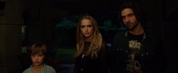 Movie still from “Lights Out” (2016), directed by David F. Sandberg – A woman standing next to two men in front of trees; Medium shot, Low angle