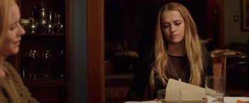 Movie still from “Lights Out” (2016), directed by David F. Sandberg – A woman sitting at a table looking at a piece of paper; Medium shot, Over the shoulder angle