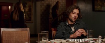 Movie still from “Lights Out” (2016), directed by David F. Sandberg – A man sitting at a table with a plate in front of him; Medium shot, Over the shoulder angle
