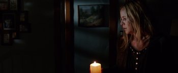 Movie still from “Lights Out” (2016), directed by David F. Sandberg – A woman sitting in front of a candle in a dark room; Medium shot, Over the shoulder angle