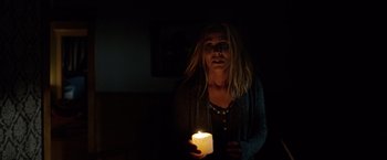 Movie still from “Lights Out” (2016), directed by David F. Sandberg – A woman holding a lit candle in a dark room; Medium shot, Over the shoulder angle