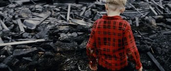 Movie still from “Little Boy” (2015), directed by Alejandro Monteverde – A boy in a red plaid shirt standing in a pile of rubble; Medium shot, High angle