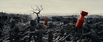 Movie still from “Little Boy” (2015), directed by Alejandro Monteverde – A man in a red jacket is standing in the middle of a pile of debris; Wide shot, High angle