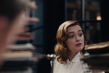 Movie still from “Living” (2022), directed by Oliver Hermanus – A woman with blonde hair and a white shirt looking into a mirror; Close Up shot, Over the shoulder angle