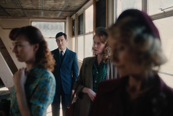 Movie still from “Living” (2022), directed by Oliver Hermanus – A group of people standing in a room; Medium shot, Over the shoulder angle