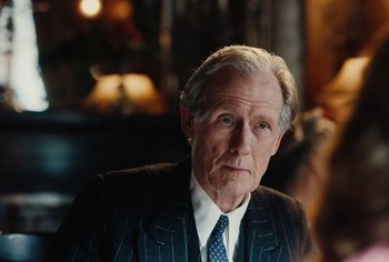 Movie still from “Living” (2022), directed by Oliver Hermanus – An older man in a suit and a tie; Close Up shot, Over the shoulder angle