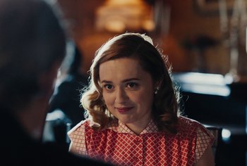 Movie still from “Living” (2022), directed by Oliver Hermanus – A person wearing a red and white dress; Close Up shot, Over the shoulder angle