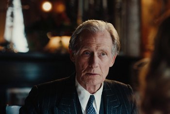Movie still from “Living” (2022), directed by Oliver Hermanus – An older man wearing a suit and tie; Close Up shot, Over the shoulder angle