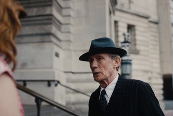 Movie still from “Living” (2022), directed by Oliver Hermanus – An older man wearing a suit and a hat; Medium shot, Low angle